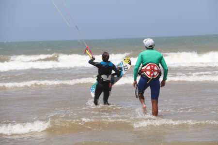 Kitesurf student learning to waterstart with kite instructor on beach in Essaouira during private kite lesson