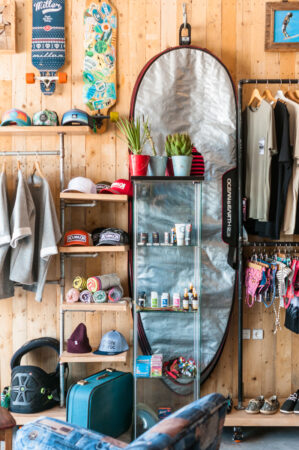 Surf shop and merchandise on wall with skateboards and surf bags in Essaouira Morocco