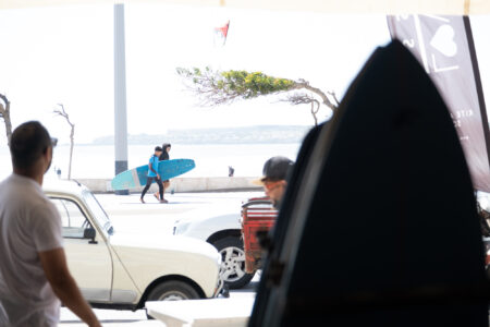 Loving surf Surf shop in Essaouira Morocco with surfers walking the boardwalk and kitesurfer riding in background