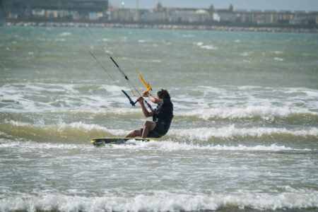 Kiter edging on the wave while kitesurfing in the bay of Essaouira beside the port