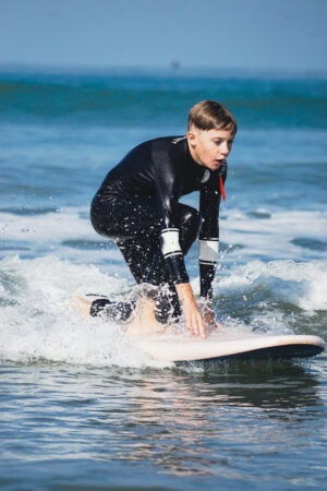 Surf student with Loving Surf Popping up on surfboard in Essaouira, Morocco